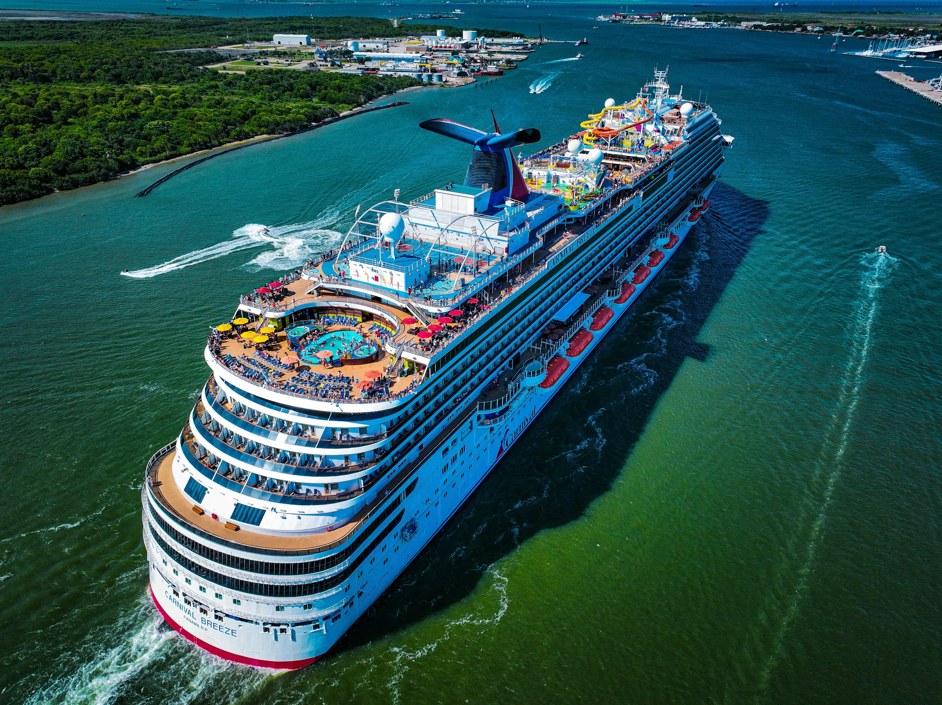 Aerial view of a cruise ship sailing through turquoise coastal waters