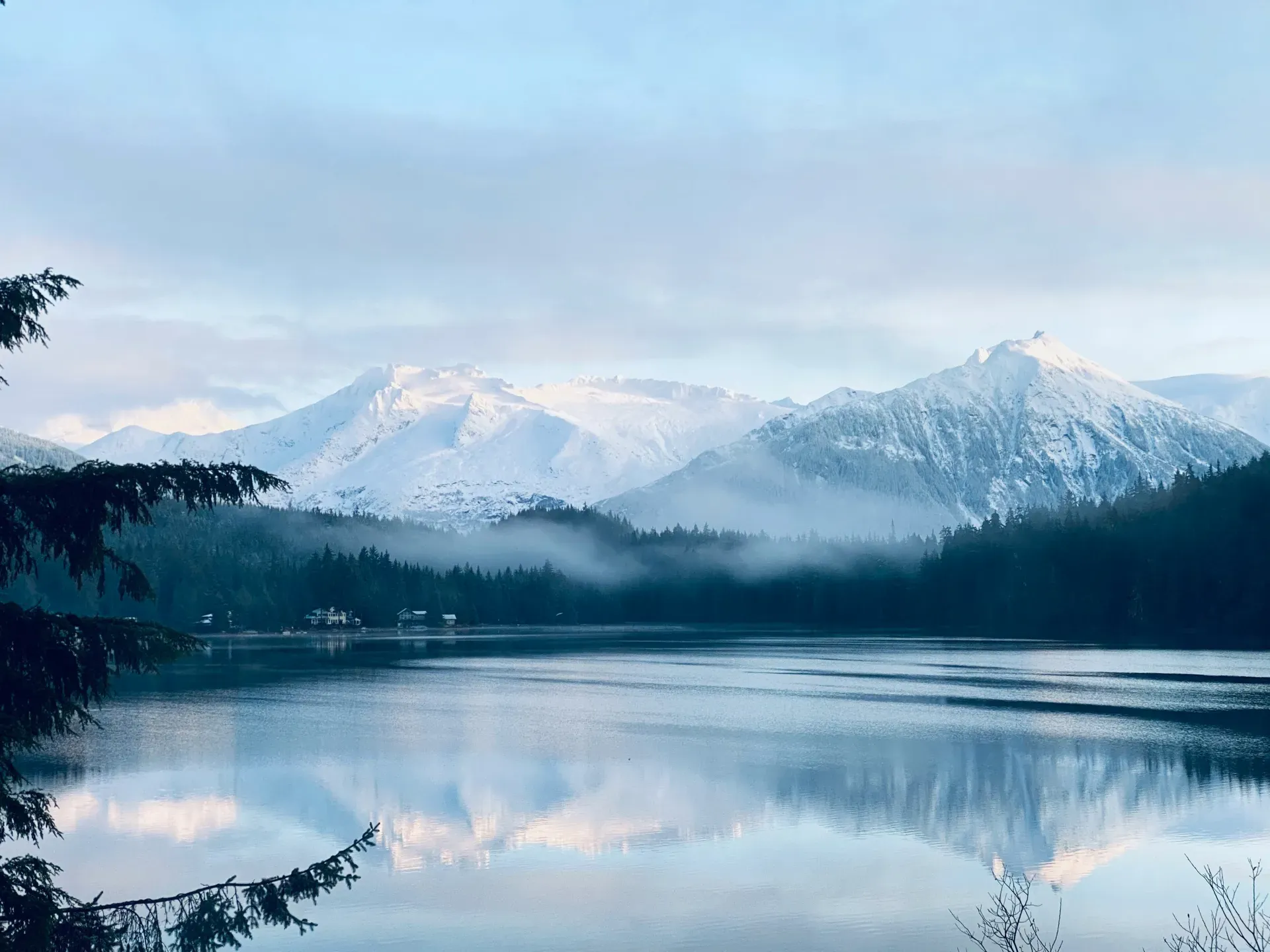 Snow-capped mountains reflected in a still lake near Juneau, Alaska