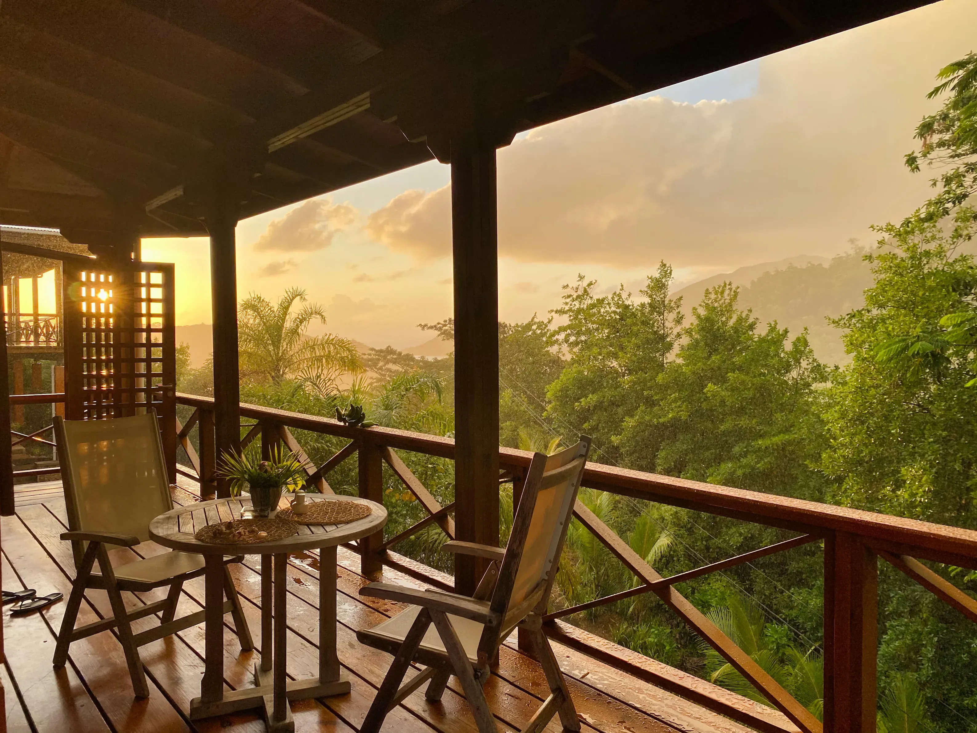 Tropical resort balcony overlooking lush green mountains at sunset